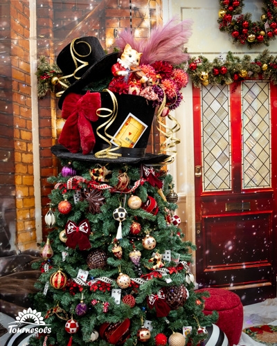 Sapin de Noël sophistiqué avec des décorations baroques devant une porte rouge ornée.